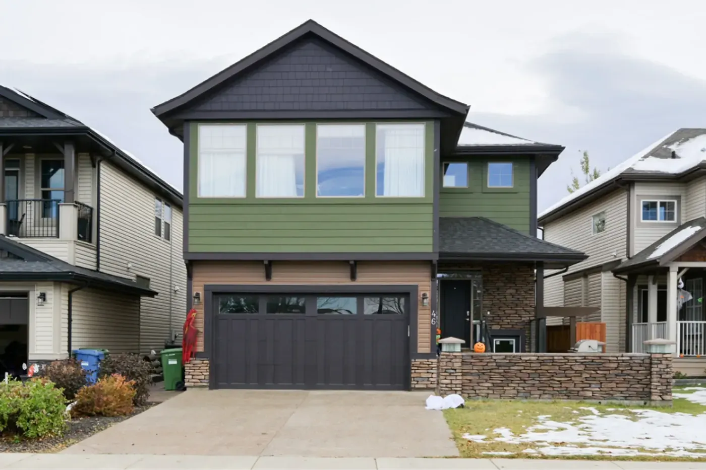 Completed home exterior front green siding garage door