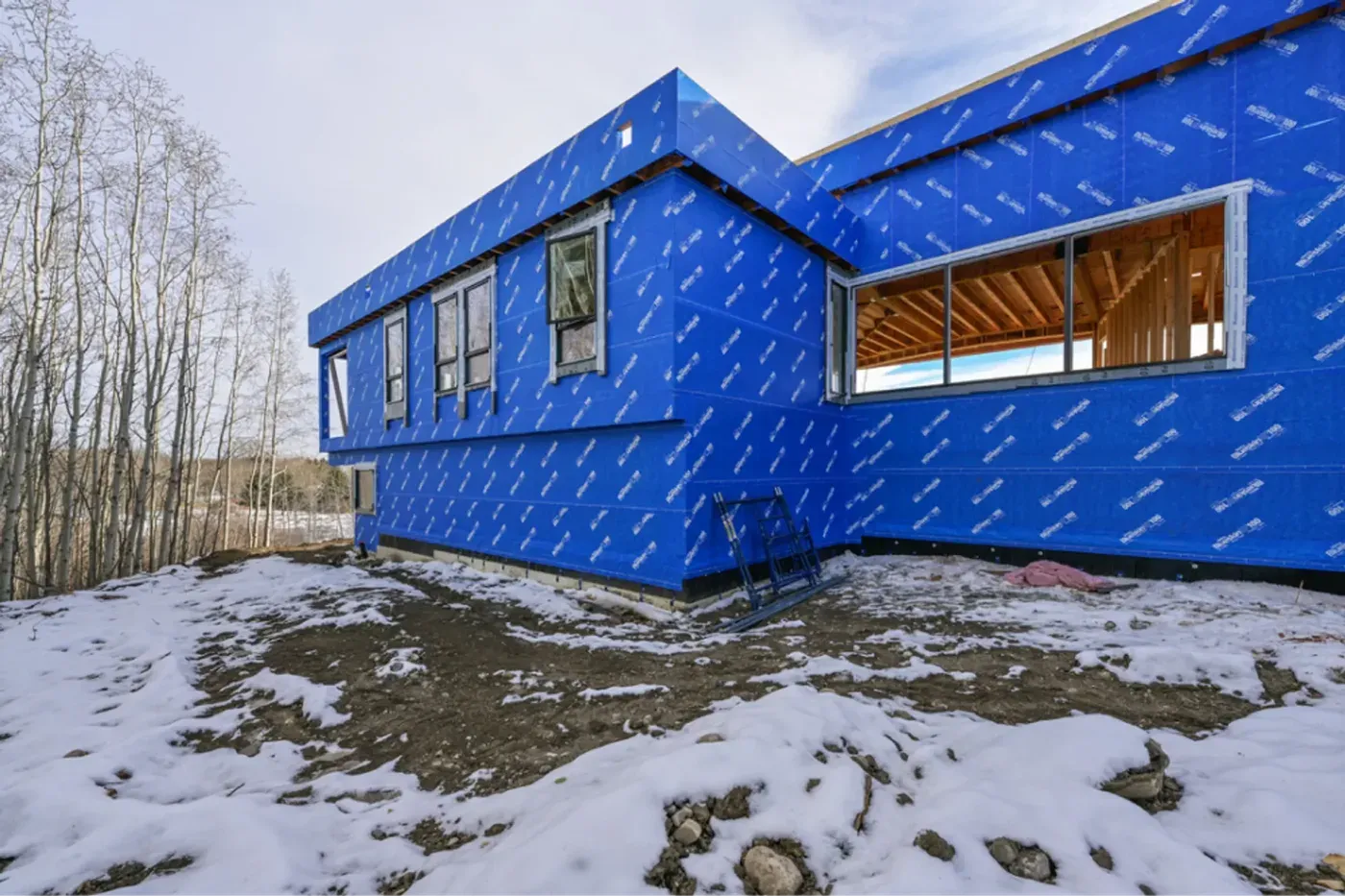 Custom home blue house wrap exterior snowy hillside