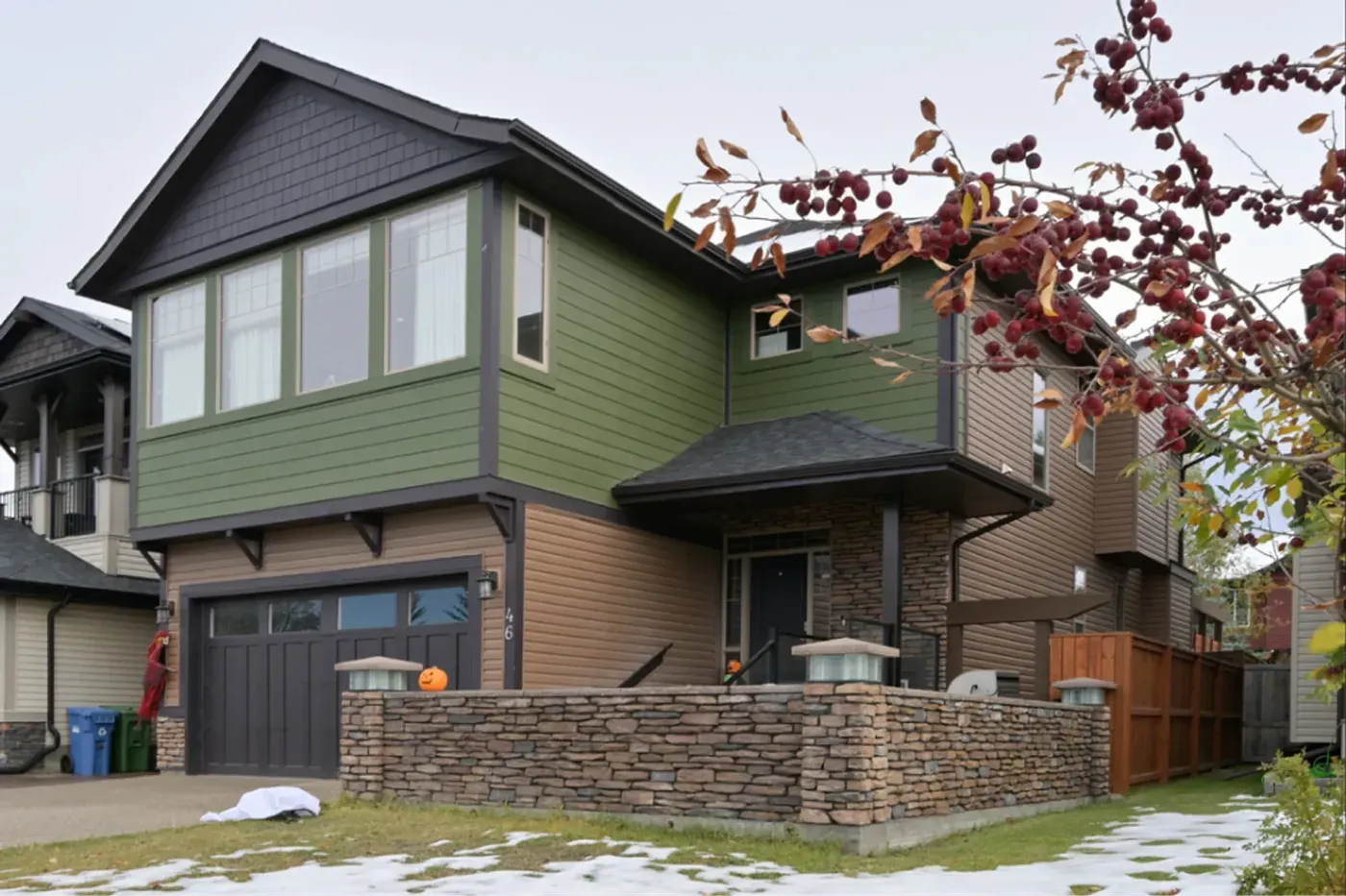 Custom home completed exterior green siding stone accent