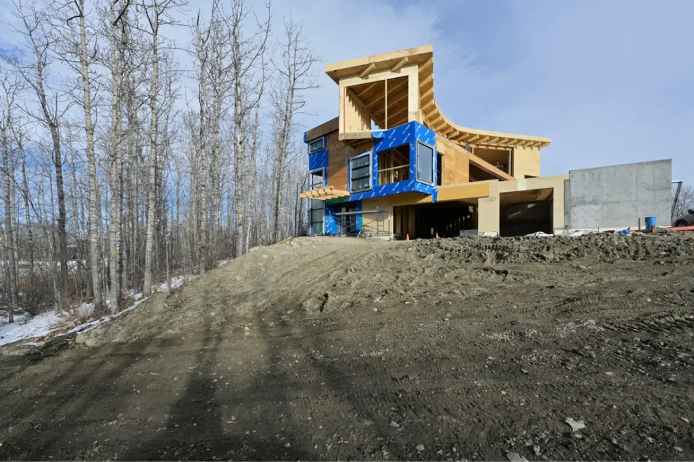 Custom home exterior blue house wrap hillside construction